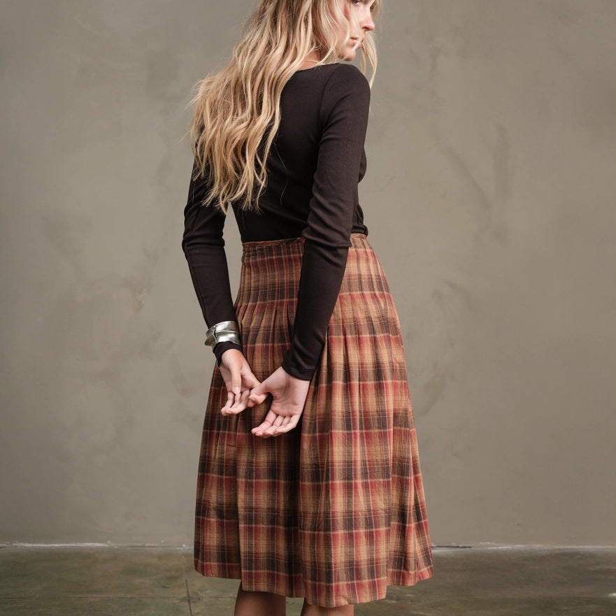 Woman wearing a plaid skirt and black top against a plain background