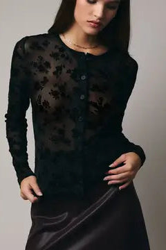 Woman wearing a black lace top and skirt against a plain background