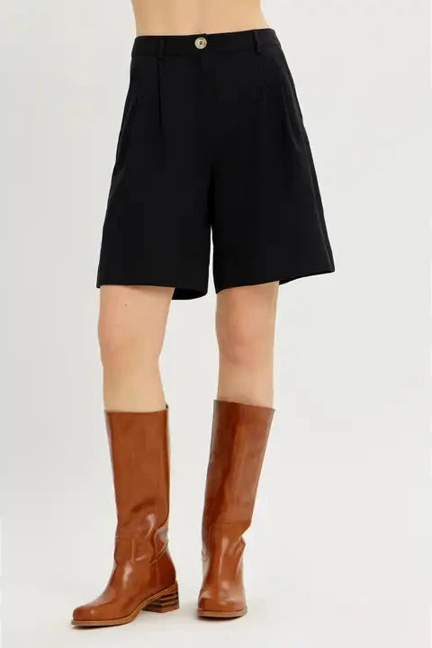 Person wearing black shorts and brown knee-high boots on a white background