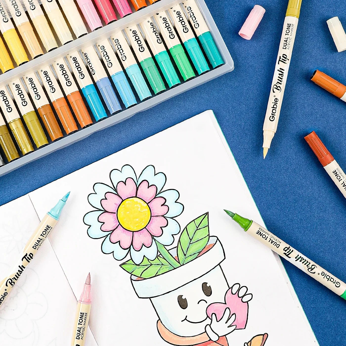 Coloring book with a flower character, Crayola markers, and colored pencils on a blue background