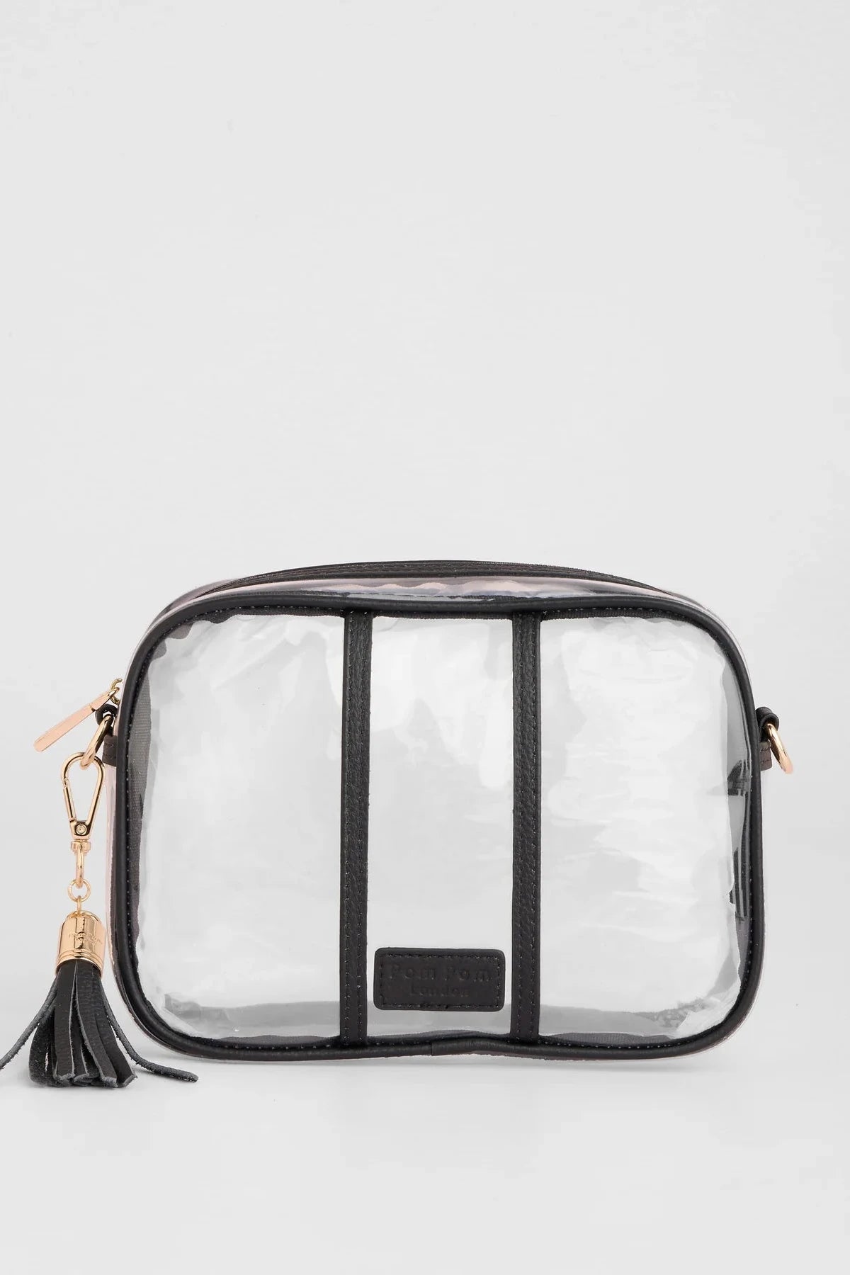 A clear plastic cosmetic pouch with black trim, black vertical straps, a black tassel zipper pull, and gold-tone hardware, shown on a light gray background.