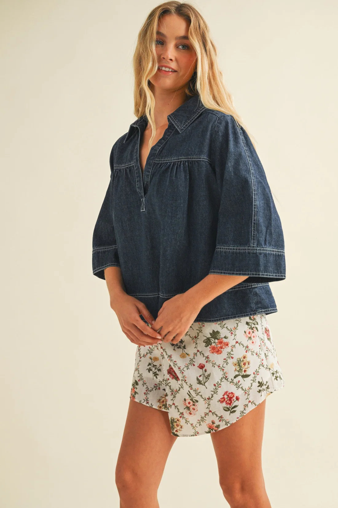Woman wearing a denim shirt and floral skirt on a beige background