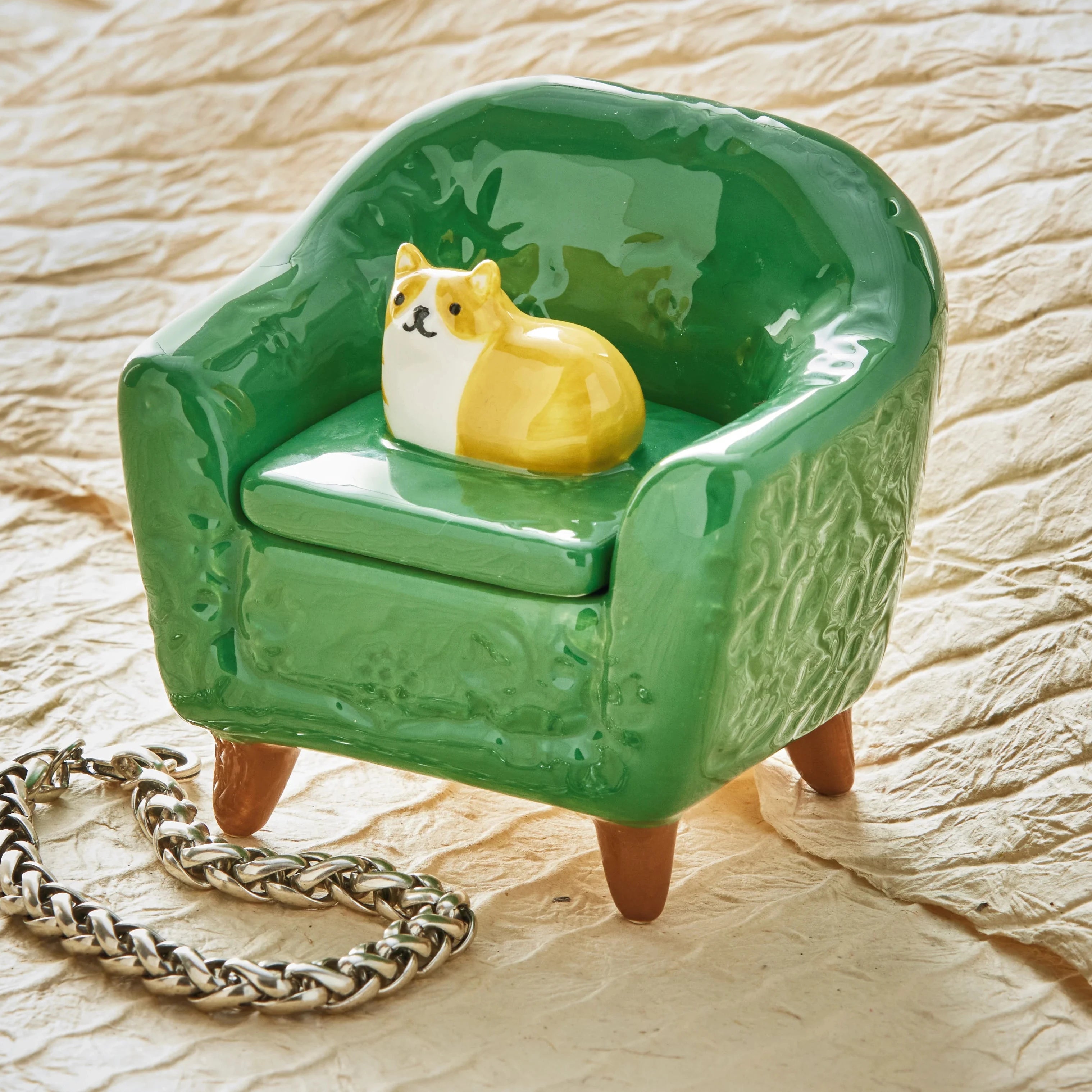 Green miniature armchair with a small dog figurine on a textured surface