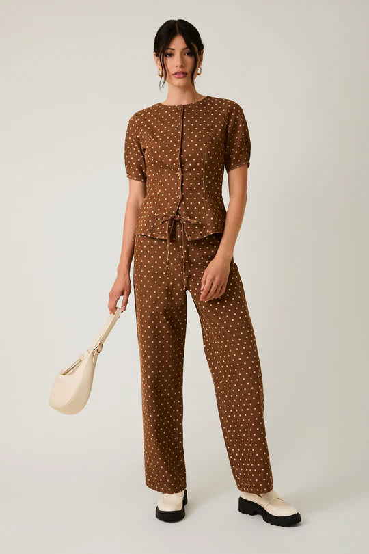 Woman wearing a brown polka dot outfit with a white background
