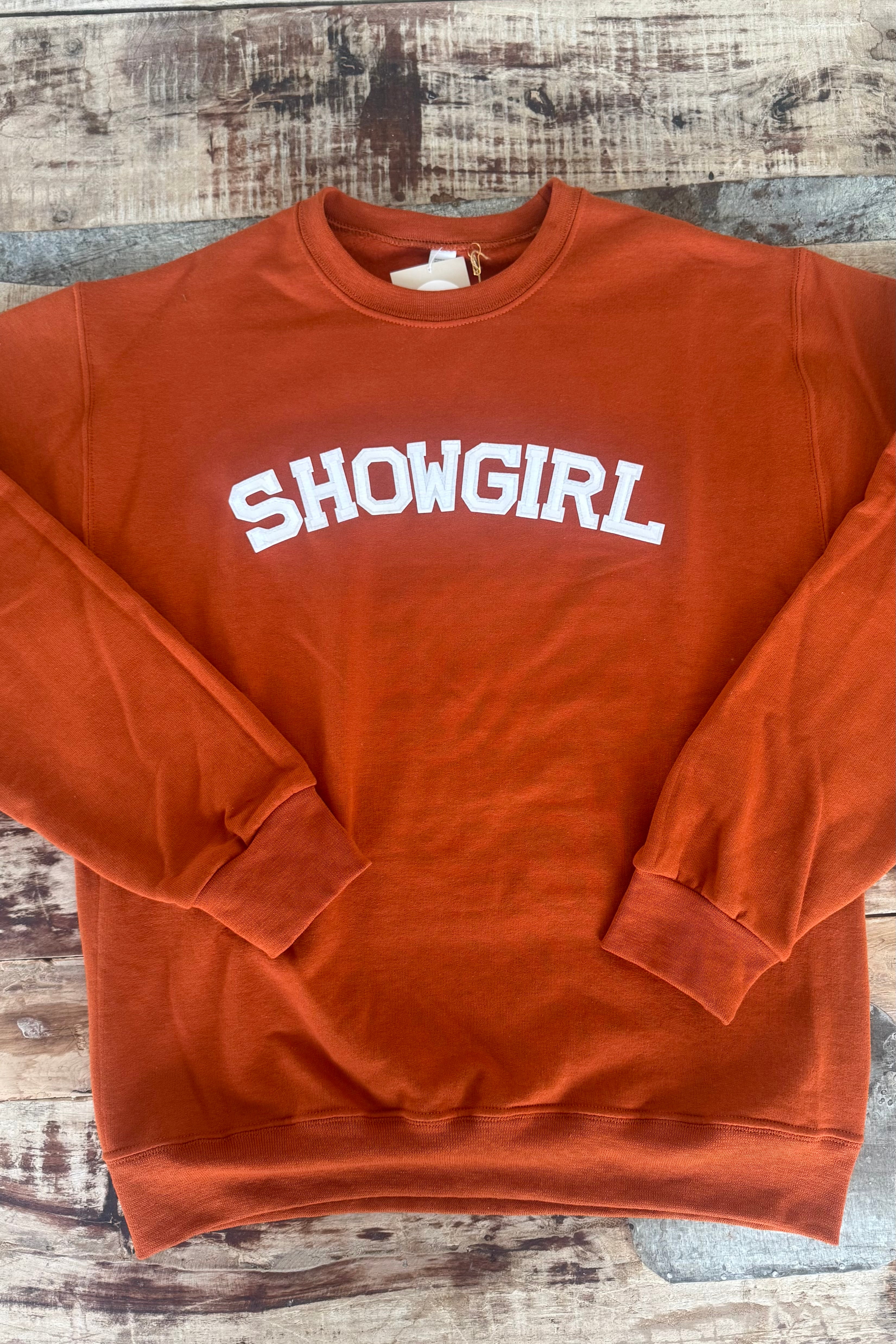 Orange sweatshirt with 'SHOWGIRL' text on a wooden surface, Life of a Showgirl Sweatshirt, Taylor Swift sweatshirt