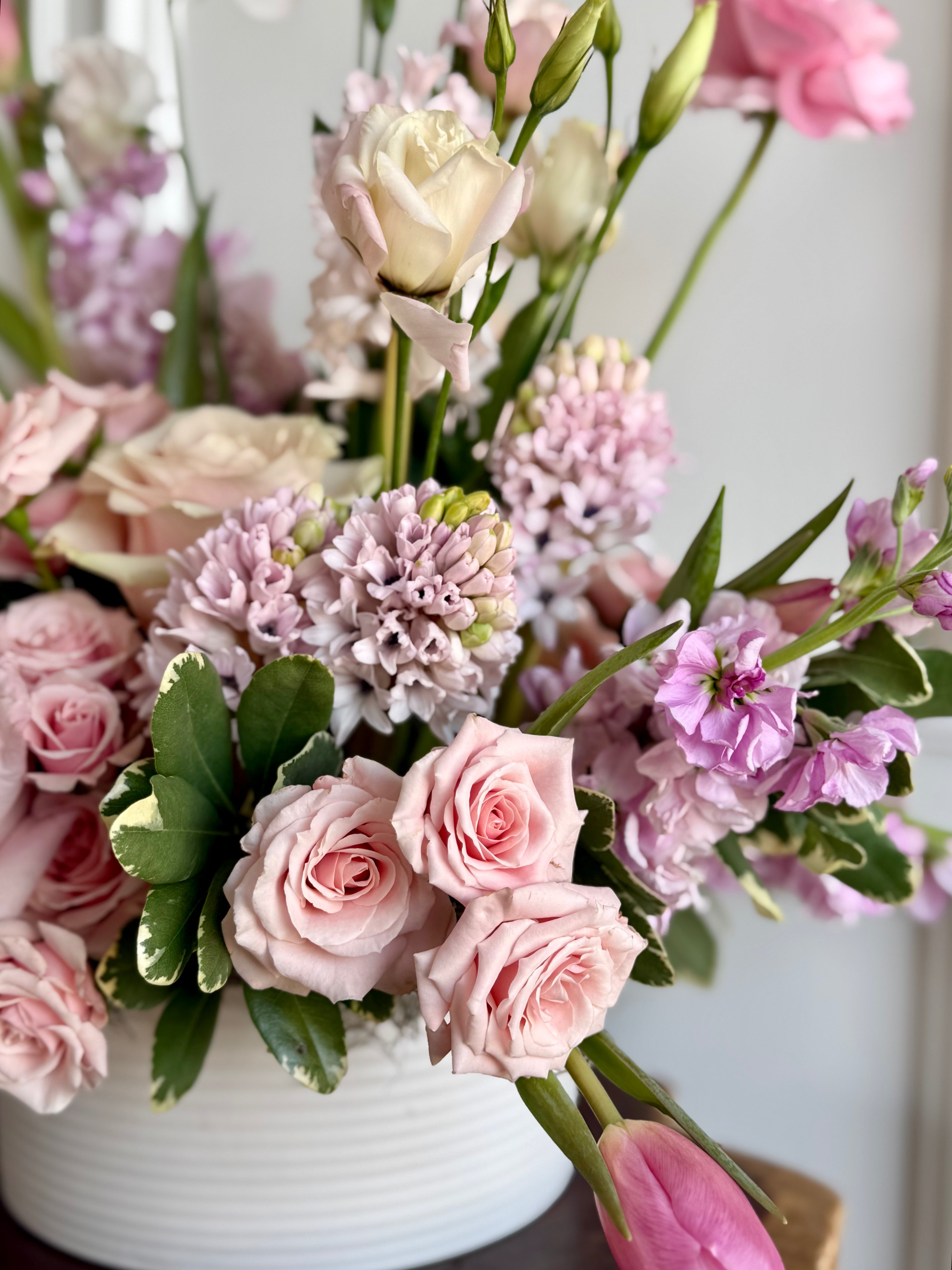 Bouquet of pink and white flowers in a white vase against a light background