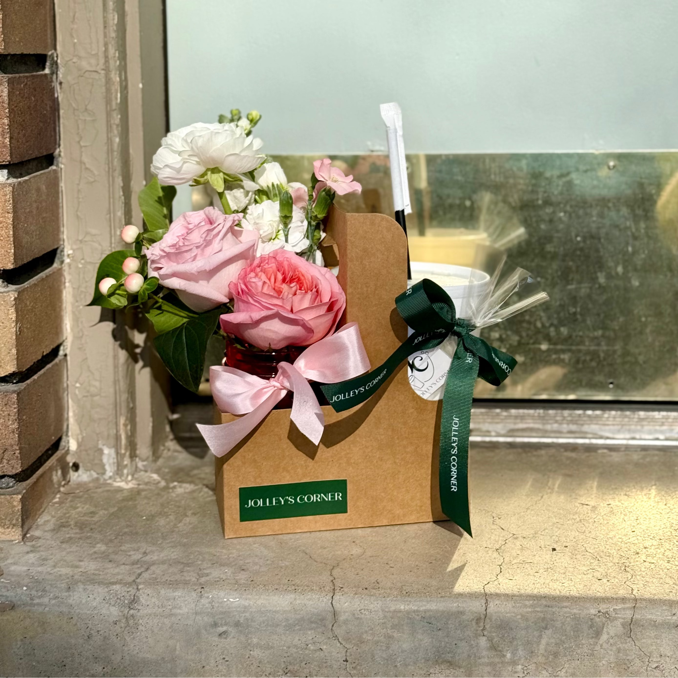 Floral arrangement in a brown box with a green ribbon on a concrete floor.