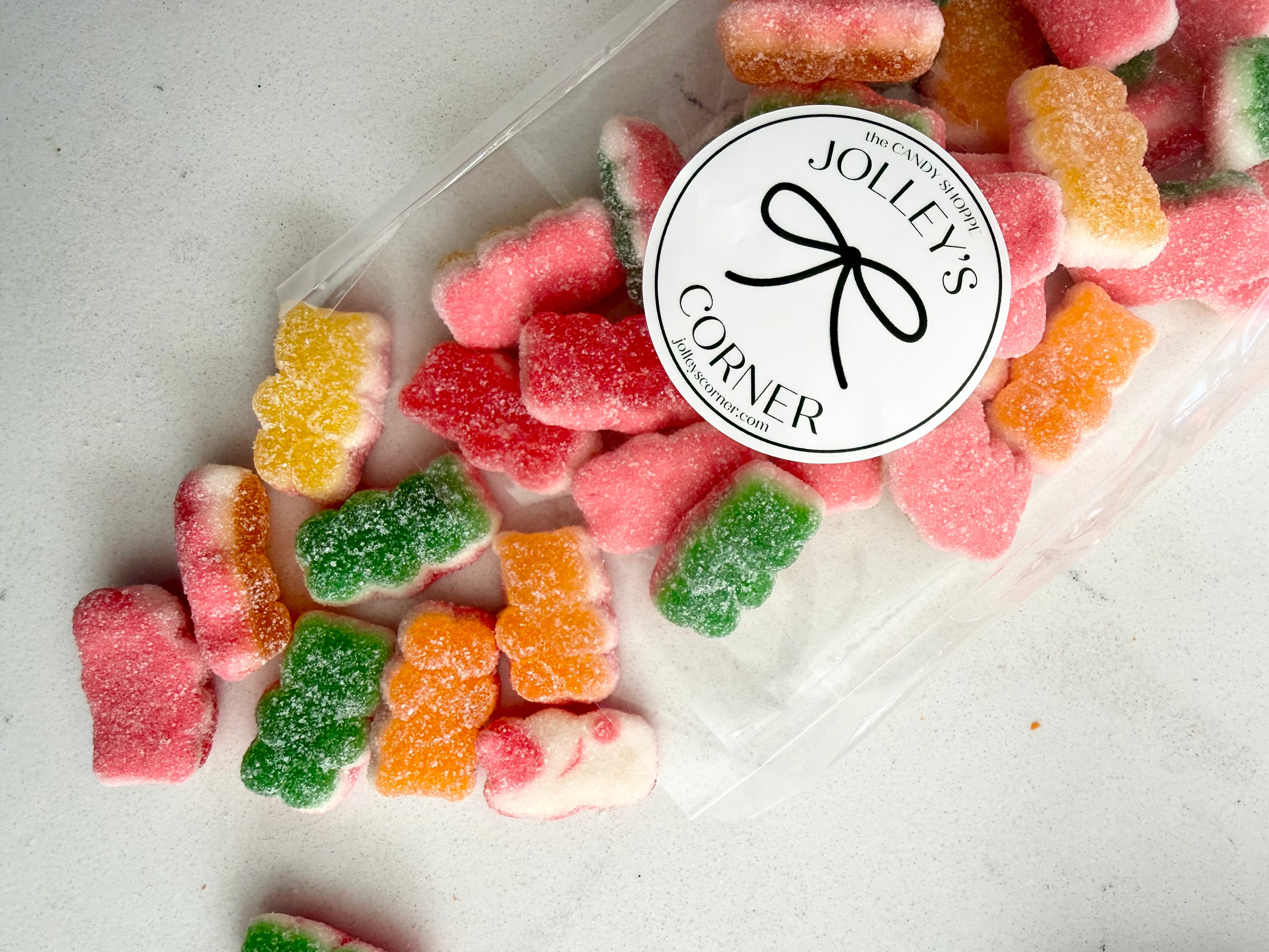 Colorful gummy bears in a clear container with Jolley's Corner logo.