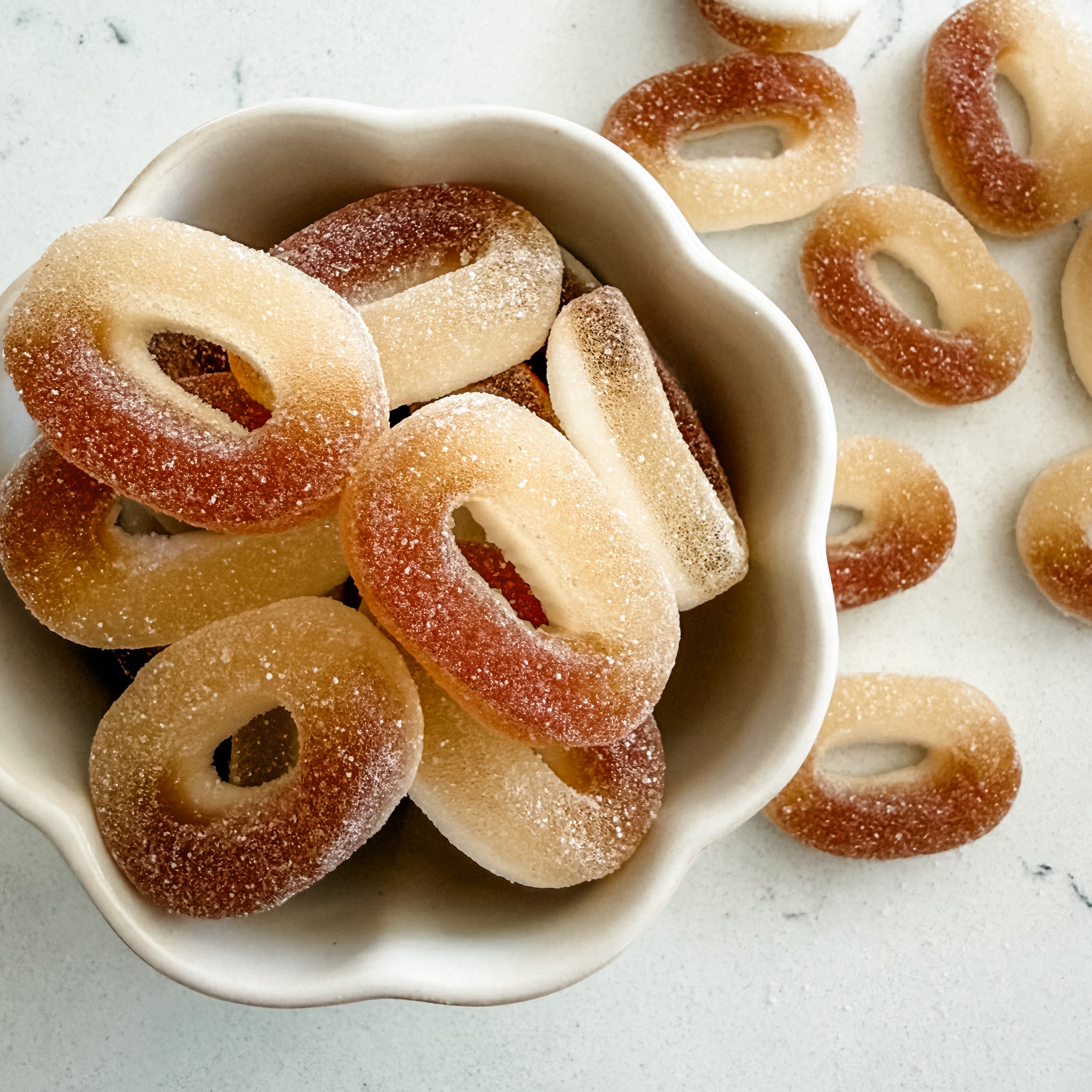 White bowl filled with sugary donut-shaped candies on a light background