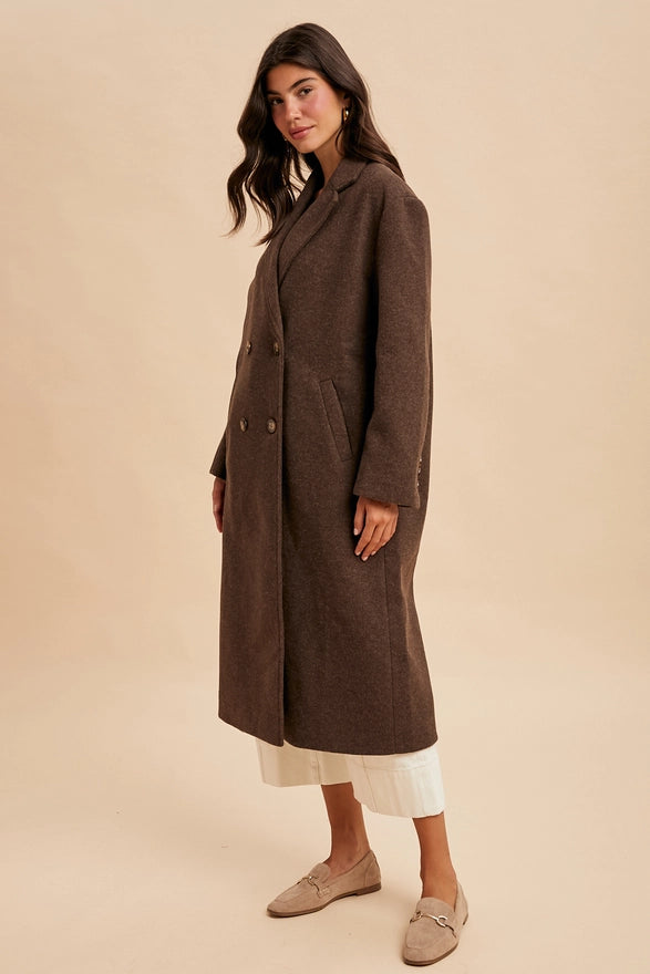 Woman wearing a long brown coat on a beige background