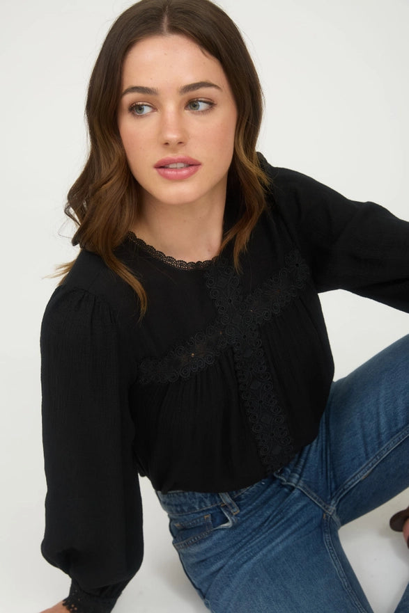 Woman wearing a black top and blue jeans against a white background
