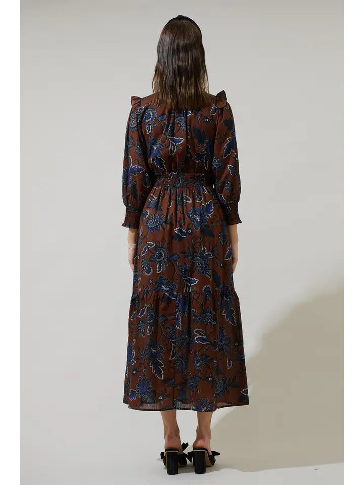 Woman wearing a long floral dress with a neutral background