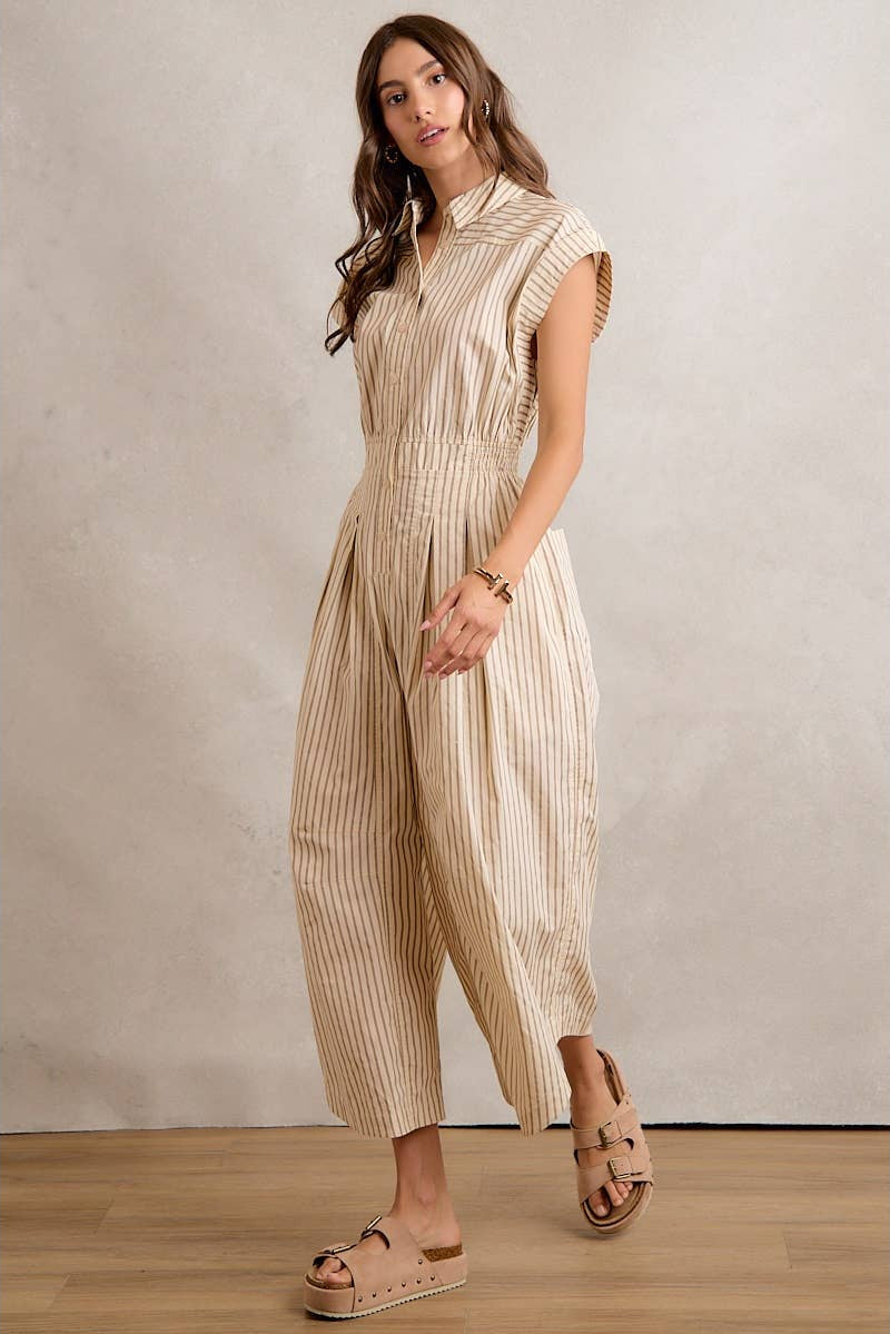 Woman wearing a beige and white striped jumpsuit against a plain background