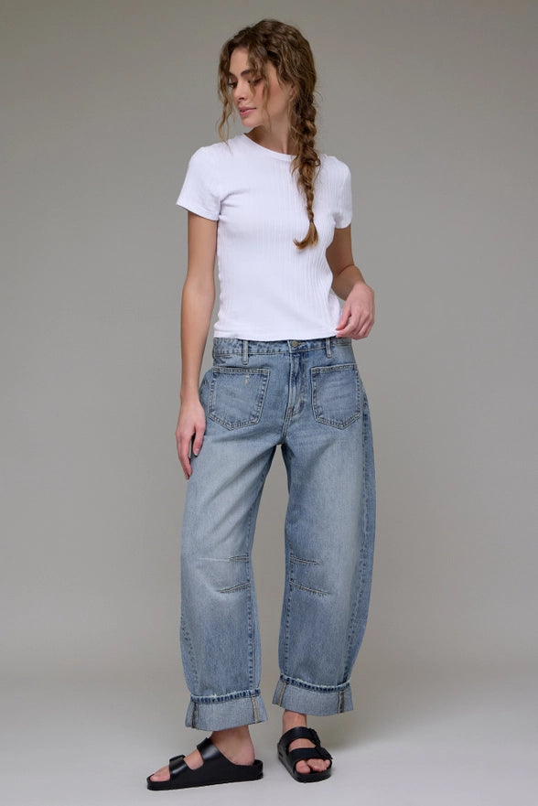 Woman wearing a white t-shirt and light blue jeans against a plain background