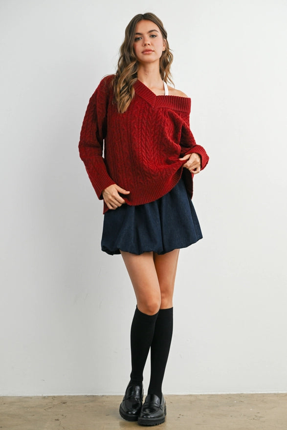 Girl Standing against a plain background wearing a V neck Wine Blue cable knit sweater with long sleeve