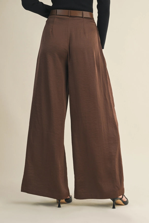 Brown wide-leg pants worn by a person on a beige background