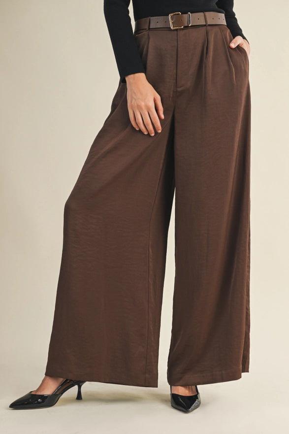 Brown wide-leg pants worn by a person on a beige background