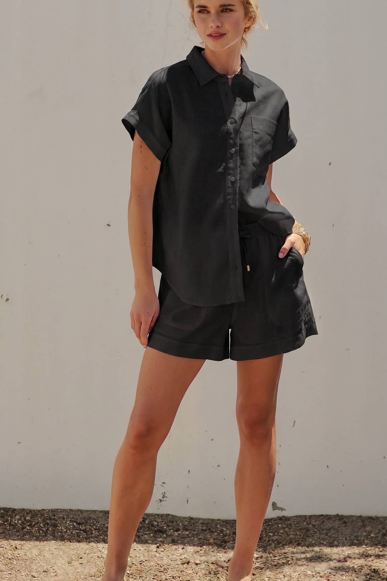 Woman wearing a black shirt and shorts against a plain background