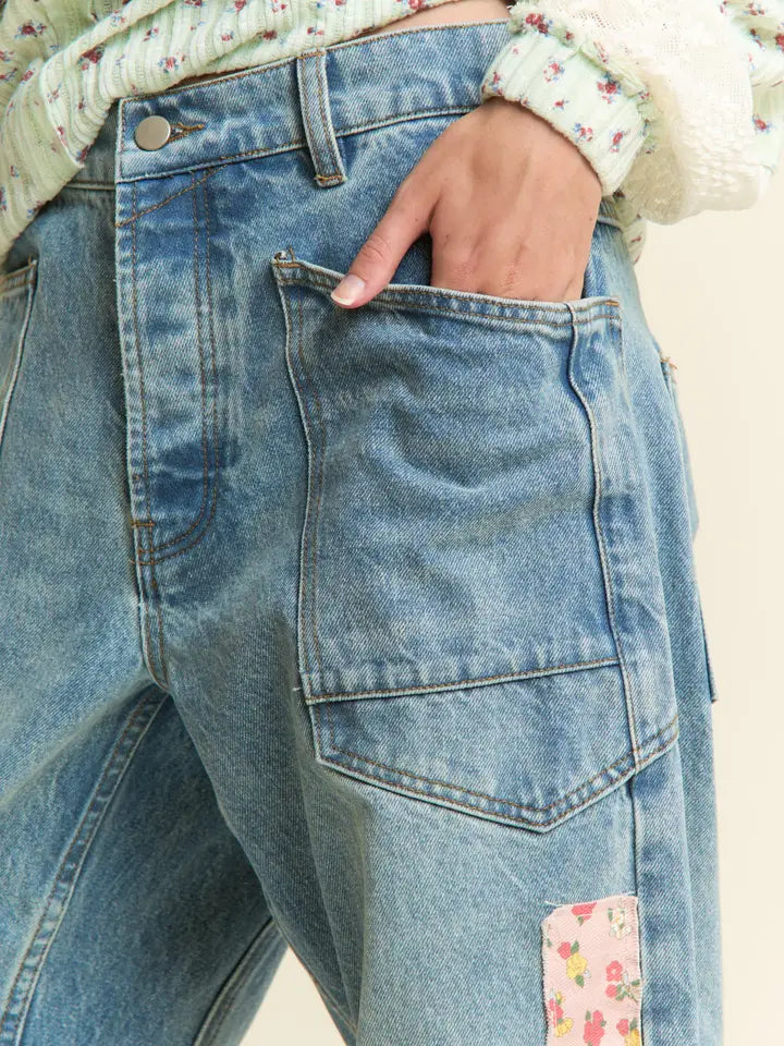 Close-up of blue jeans with floral patch on a neutral background