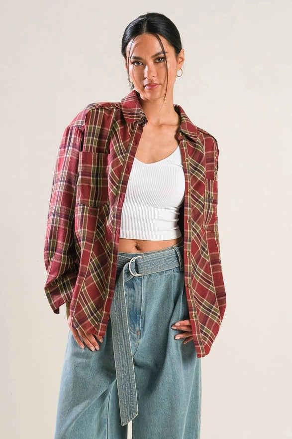 Woman wearing a plaid shirt over a white top and blue jeans on a plain background