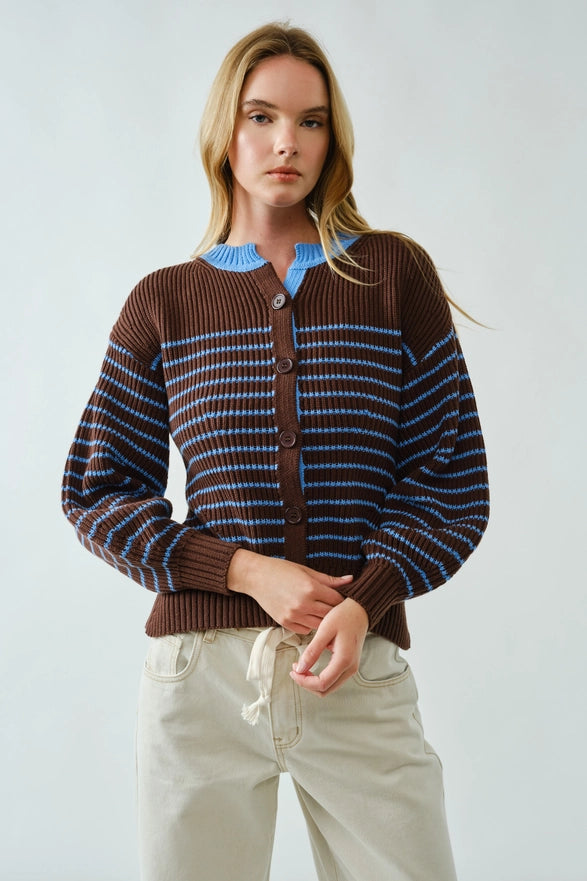 Woman wearing a brown and blue striped sweater with a plain background