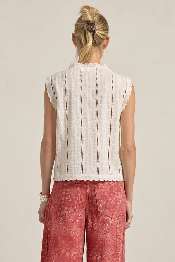 Woman wearing a white sleeveless top and red patterned pants on a beige background