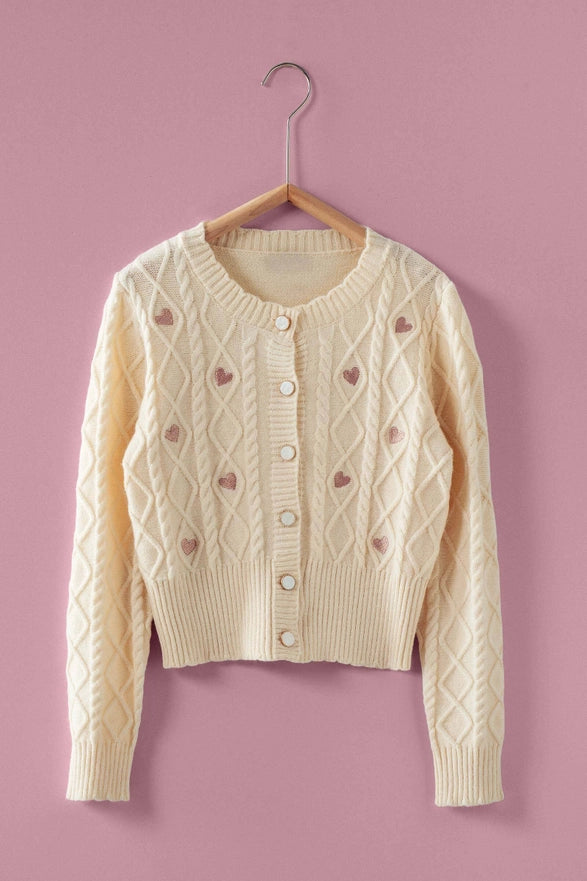 Cream-colored sweater with heart patterns on a pink background