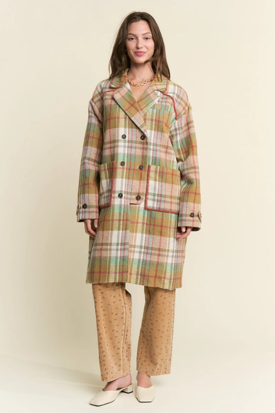 Woman wearing a plaid coat and patterned pants against a beige background