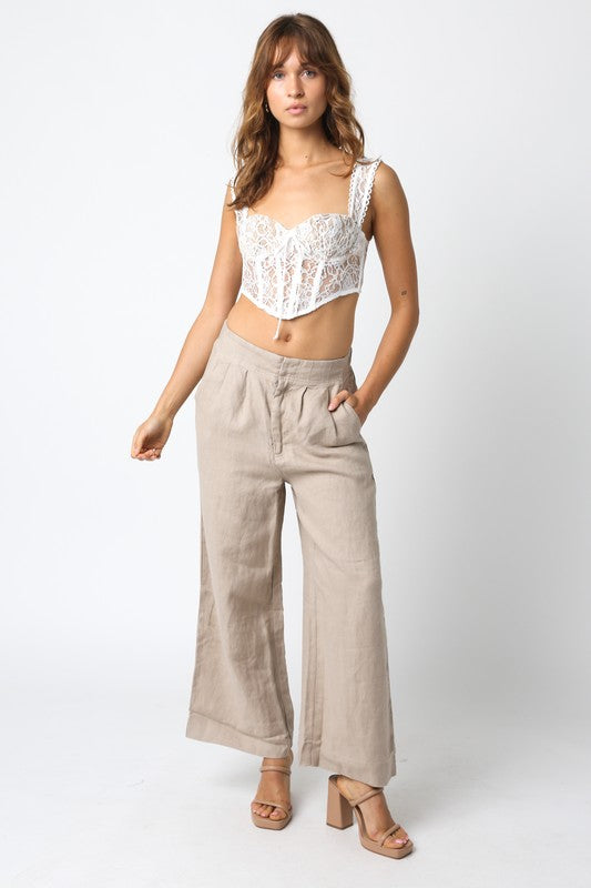 Woman wearing a white lace top and beige wide-leg pants on a white background