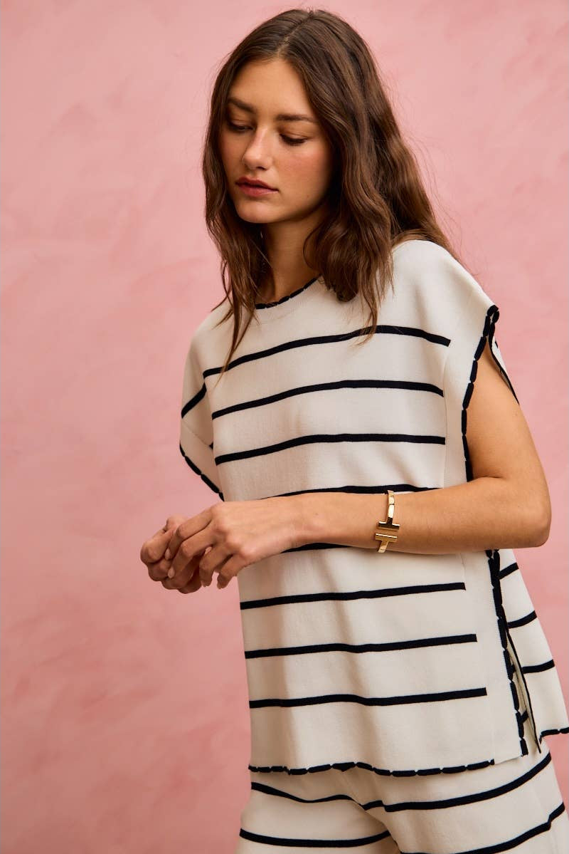 Woman wearing a black and white striped dress against a pink background
