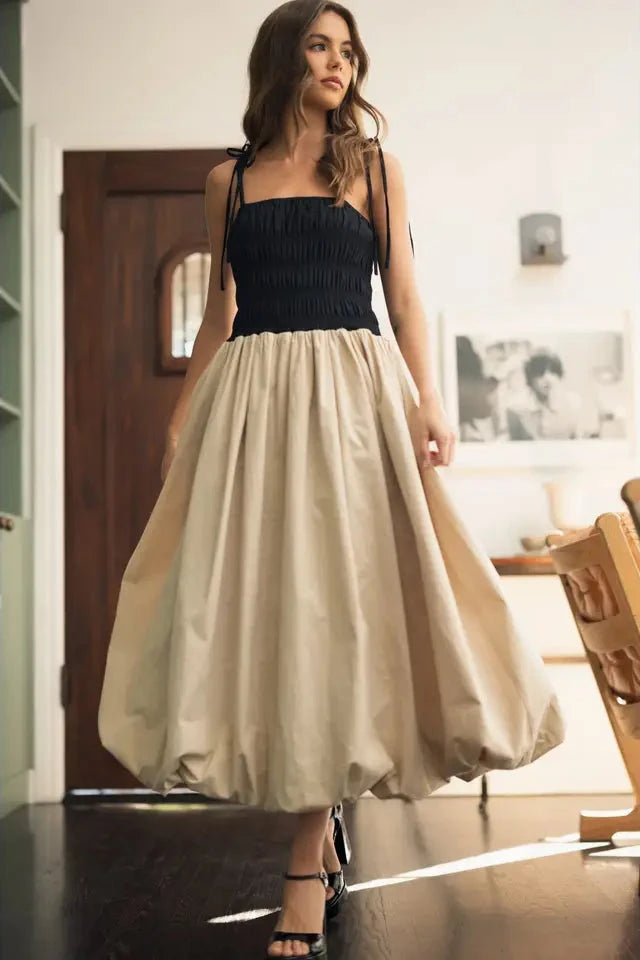 A model wearing a contrasting top balloon dress with a black bodice and beige skirt.