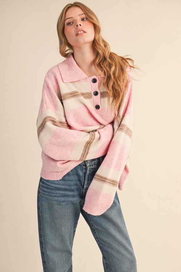 Woman wearing a pink plaid sweater with black buttons on a beige background