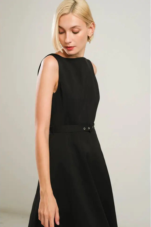 Woman wearing a black sleeveless dress against a plain background
