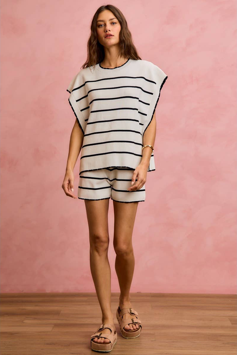 Woman wearing a black and white striped outfit against a pink wall.