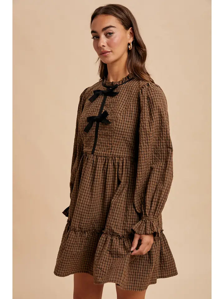 Woman wearing a brown checkered dress with black bows on a beige background