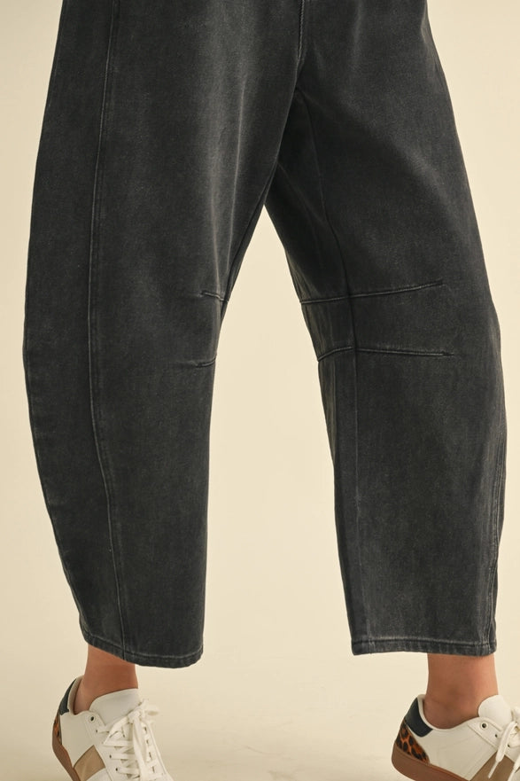 Black denim pants worn by a person on a beige background