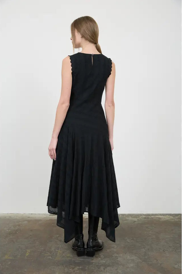 Woman wearing a black dress standing against a white wall.