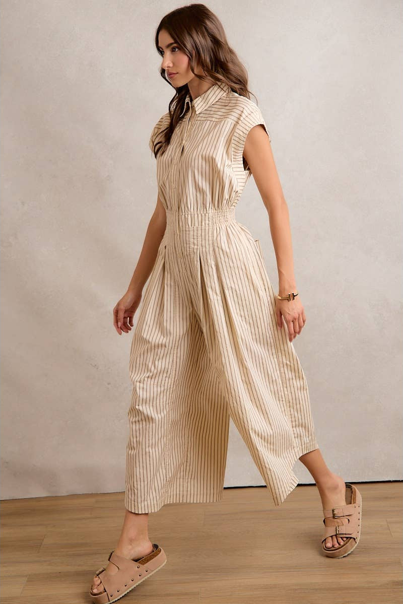 Woman wearing a beige striped jumpsuit against a plain background