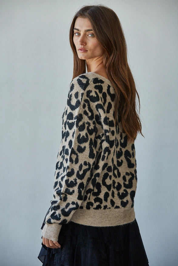 Woman wearing a leopard print sweater against a plain background