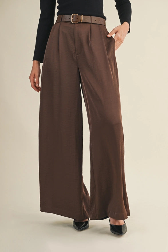 Brown wide-leg pants worn by a person on a beige background