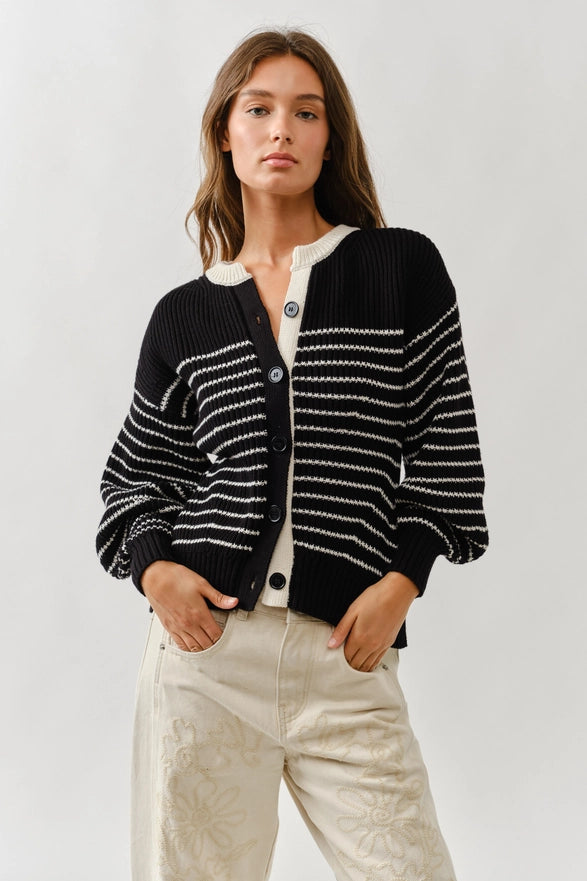 Woman wearing a black and white striped cardigan on a plain background