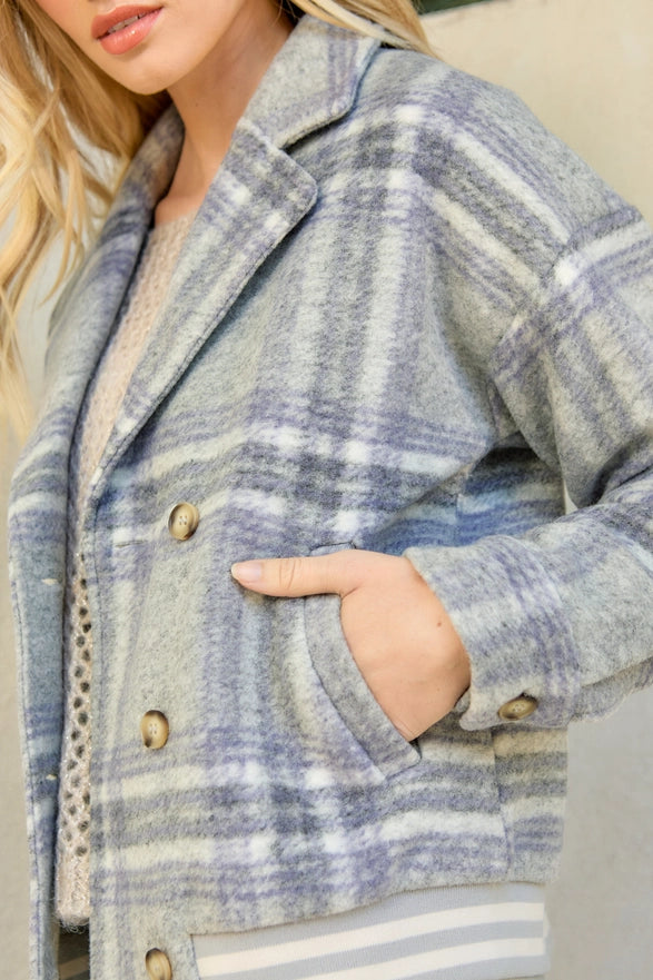 Person wearing a blue plaid coat with a neutral background