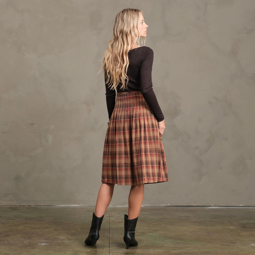 Woman wearing a plaid skirt and black top against a plain background