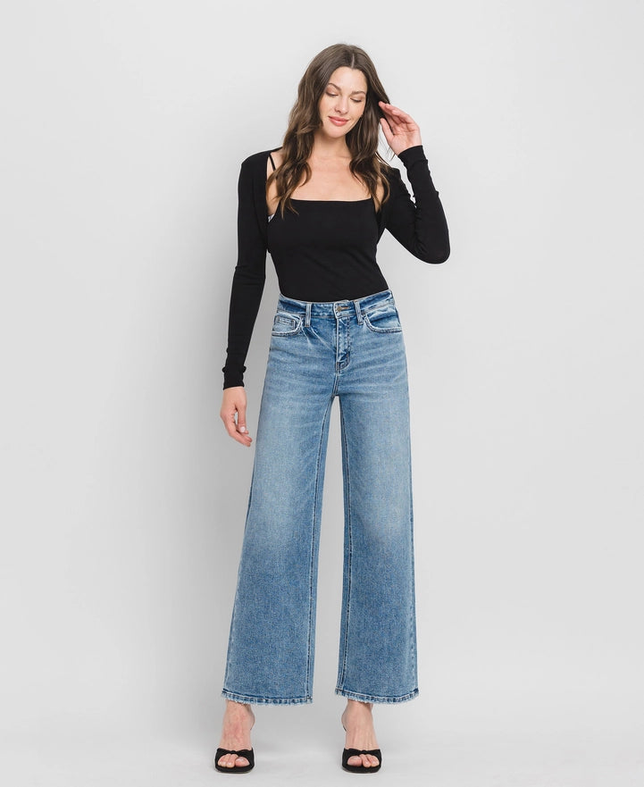 Woman wearing blue jeans and a black top against a white background
