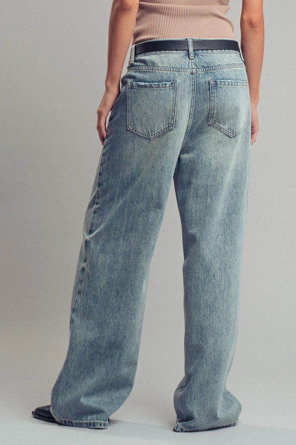 Person wearing light blue jeans on a plain background