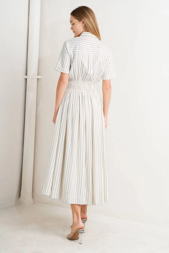 Woman wearing a white and gray striped dress in a minimalistic setting
