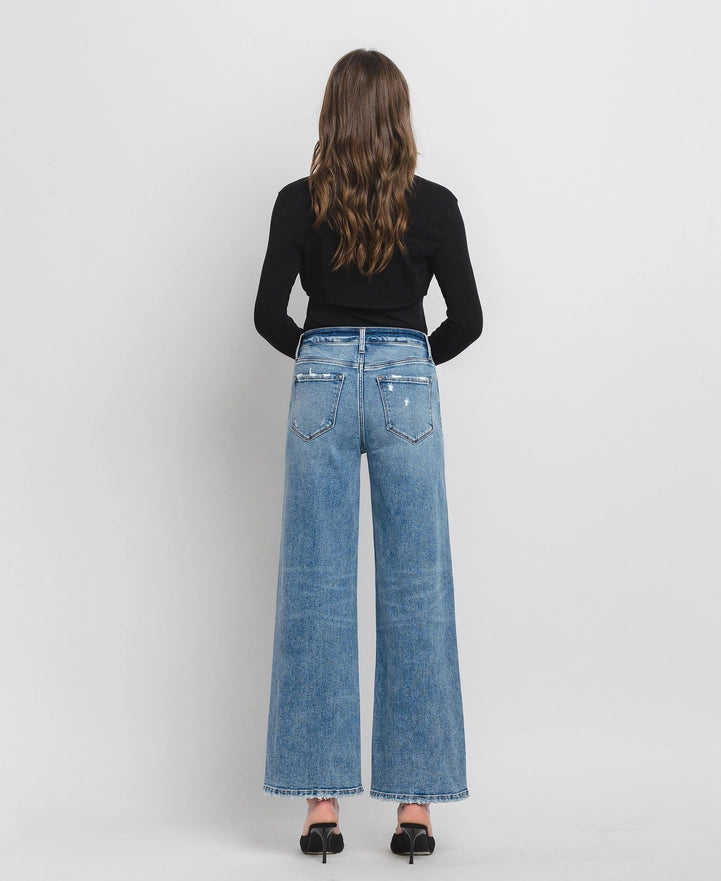 Woman wearing blue jeans and a black top on a white background