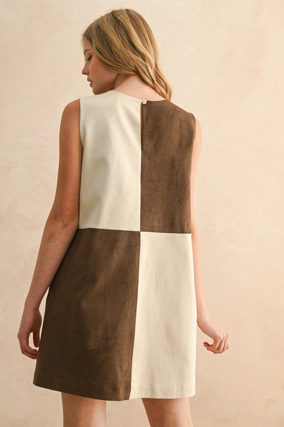 Woman wearing a two-tone dress with brown and white sections on a beige background