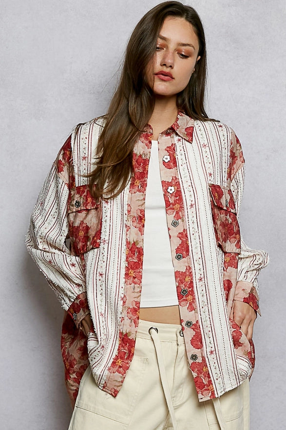 Woman wearing a floral and striped shirt over a white top with beige pants on a gray background