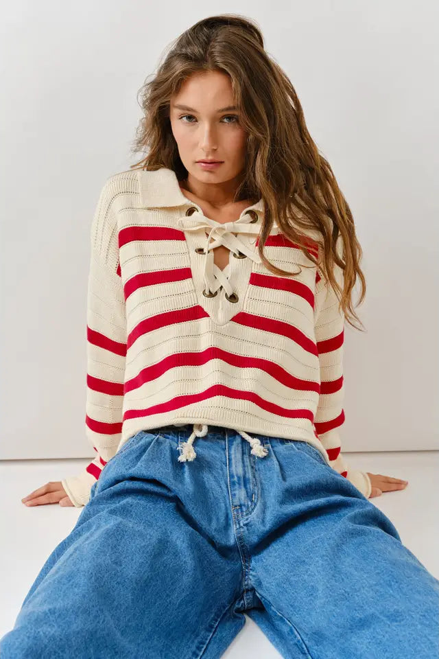 Woman wearing a red and white striped sweater with blue jeans on a plain background